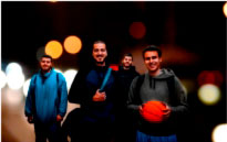 Four men smiling with a background of lights out of focus.